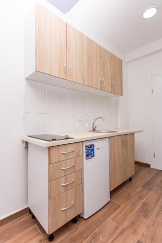 a kitchen with wooden cabinets and a white refrigerator at Resort Bevilacqua in Budva