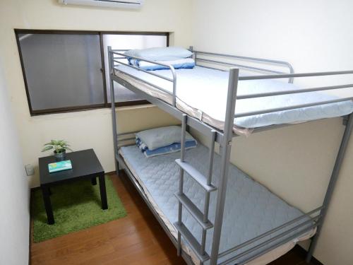 a bunk bed room with two bunk beds and a table at Guest House Twenty-Seven 27 in Osaka