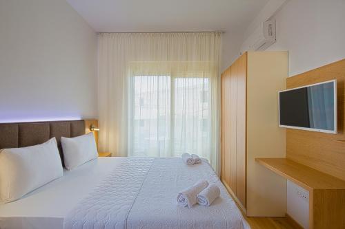 a bedroom with a bed with a television and two slippers at Eukaliptus in Becici