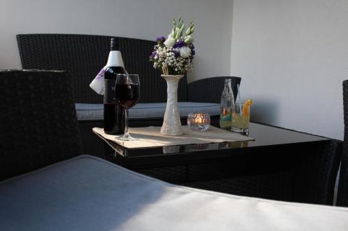 a table with a glass of wine and a vase of flowers at B&B Millenium House in Plitvička Jezera