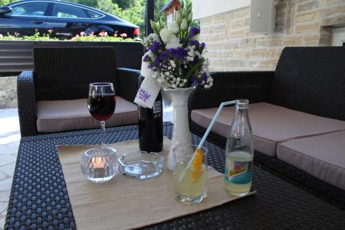 a table with wine glasses and a vase of flowers at B&B Millenium House in Plitvička Jezera