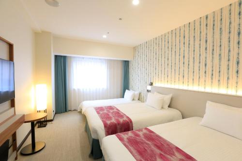 a hotel room with two beds and a television at Hotel JAL City Naha in Naha