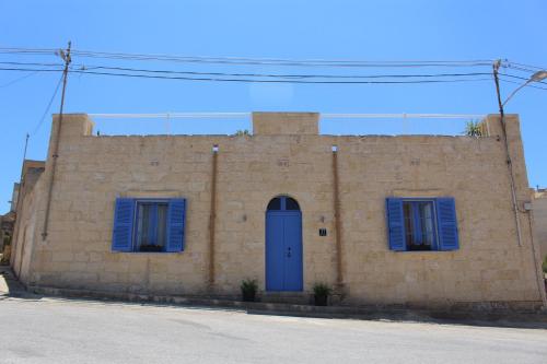 a brick building with blue shutters and a blue door at Simar in Qala
