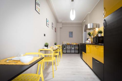 a kitchen with yellow cabinets and tables and yellow chairs at Audrey Rooms in Rome