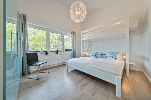a bedroom with a bed and a chair and windows at Ferienwohnung Meeschendorf in Fehmarn