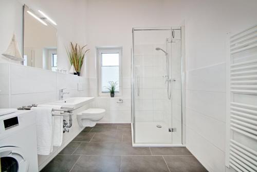 une salle de bain blanche avec une douche et un lavabo dans l'établissement Ferienwohnung Meeschendorf, à Fehmarn