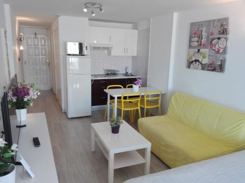 sala de estar con sofá amarillo y cocina en Borinquen Private Homes, en Playa de las Américas