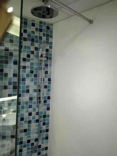 a bathroom with a shower with blue tiles on the wall at Maison Mitwaba in Nairobi