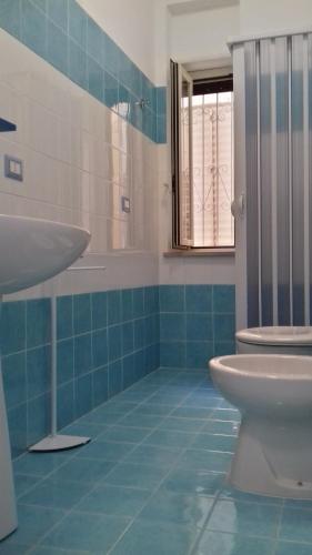 a blue tiled bathroom with a sink and a toilet at Il Corvino in Diamante
