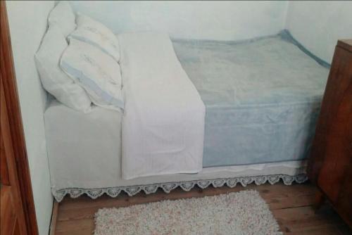 una cama con sábanas blancas en una habitación en Small room for two in private villa, en Korçë