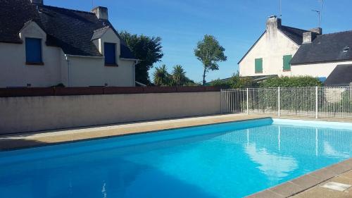 a swimming pool next to a fence and a house at Les vacances aux Pouldu in Clohars-Carnoët