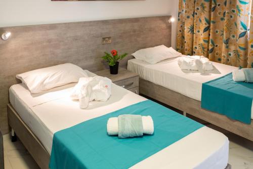 two beds in a hotel room with towels on them at For Rest Aparthotel in St Paul's Bay