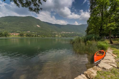 a orange kayak sitting on the shore of a lake at CASA VACANZA Residence Lago di Endine in Monasterolo del Castello