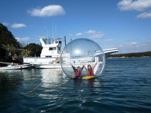 two people are in a ball in the water at Tabinoyado Ushionoakari Geiboso in Shima