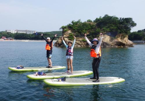 three people on paddle boards in the water at Tabinoyado Ushionoakari Geiboso in Shima