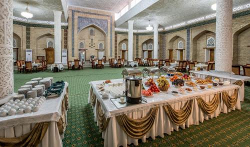a banquet hall with two tables with food on them at Orient Star Khiva Hotel- Madrasah Muhammad Aminkhan 1855 in Khiva