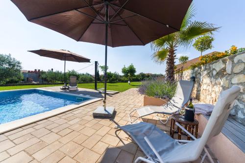 a patio with chairs and an umbrella and a pool at Apartment Alex in Zadar