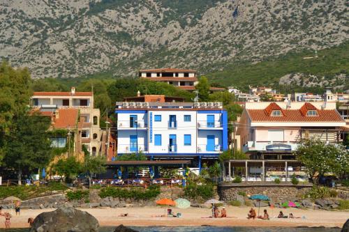 eine Gruppe von Menschen an einem Strand mit Gebäuden in der Unterkunft Hotel La Favorita in Cala Gonone