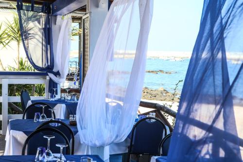 a restaurant with blue tables and chairs and the ocean at Hotel La Favorita in Cala Gonone