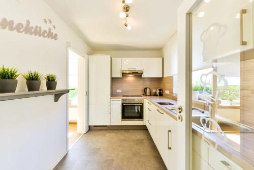 eine Küche mit weißen Schränken und Topfpflanzen in der Unterkunft Ferienhaus Vier Jahreszeiten in Bad Urach