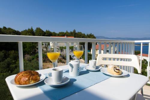 una mesa con comida y vasos de zumo de naranja y pan en Apartments Villa Olea en Lumbarda