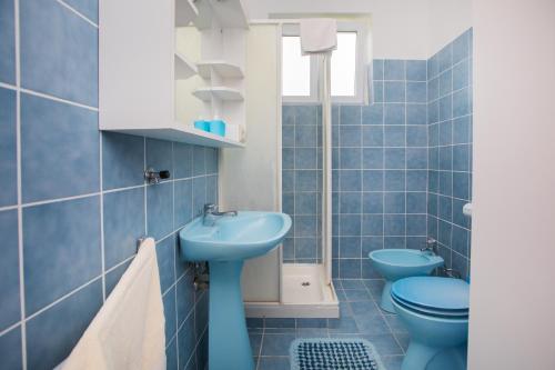 a blue bathroom with a sink and a toilet at Apartmani Branko Lemac in Brodarica