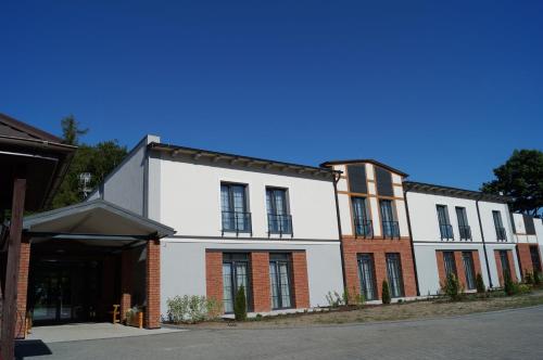a white building with black windows on a street at Ośrodek Turystyczny Warzenko in Warzenko