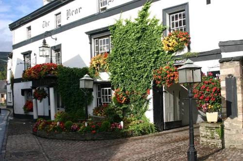 a white building with flowers in front of it at Bear Crickhowell in Crickhowell