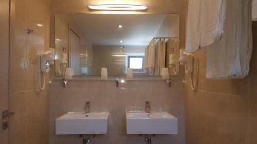 a bathroom with two sinks and a large mirror at Hotel Prassino Nissi in Moraitika