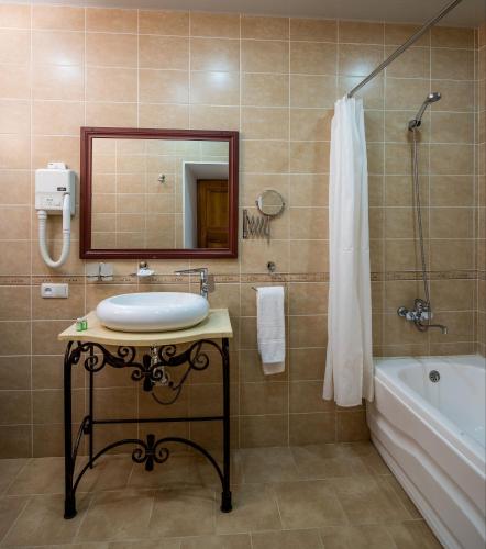 a bathroom with a sink and a tub and a mirror at Orient Star Khiva Hotel- Madrasah Muhammad Aminkhan 1855 in Khiva