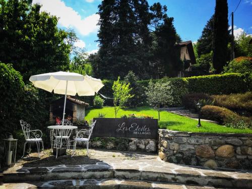 a table and chairs with an umbrella in a garden at Bellagio Les Etoiles in Bellagio