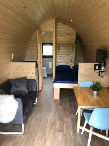 a living room of a tiny house with a couch and a table at Camping Ginsterveld in Burgh Haamstede