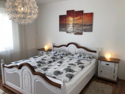 a bedroom with a white bed with two tables and a chandelier at Ferienwohnung "Am Nordertor" in Flensburg