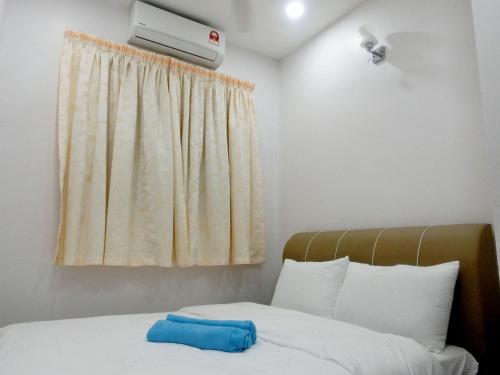- une chambre avec un lit et une serviette bleue dans l'établissement Taiping Cozy Homestay II, à Taiping