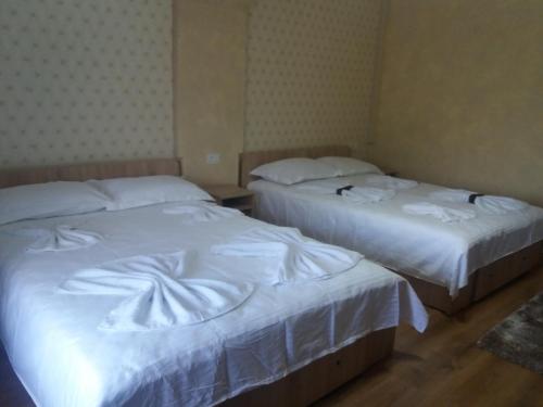 two beds in a hotel room with white sheets at Casa Lipianu in Târgu Jiu