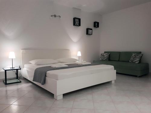 a white bedroom with a bed and a couch at Apartments Saric 2 in Jadrija