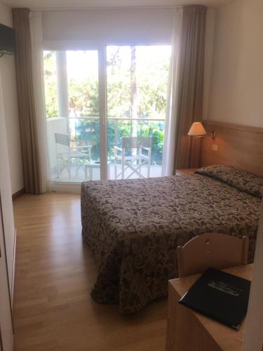 a hotel room with a bed and a sliding glass door at Hotel Bellevue in Lignano Sabbiadoro