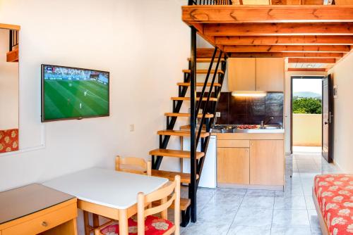 a kitchen and a dining room with a tv on the wall at Sunday Hotel in Ialyssos