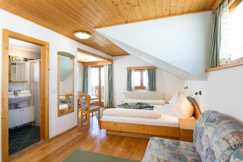 a bedroom with a bed and a couch in a room at Sattleggers Alpenhof & Feriensternwarte in Berg im Drautal