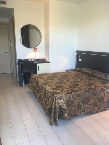 a bedroom with a bed and a desk and a mirror at Hotel Bellevue in Lignano Sabbiadoro