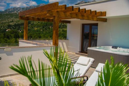 a balcony with a hot tub and a wooden pergola at Villa Grandioza in Seline