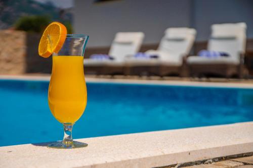 a glass of orange juice sitting next to a swimming pool at Villa Grandioza in Seline