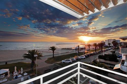 a view from a balcony of a street with a sunset at Hôtel Café Miramar in Le Grau-du-Roi