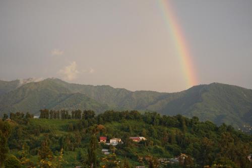 a rainbow over a mountain with houses and trees at AnaMaria in Batumi