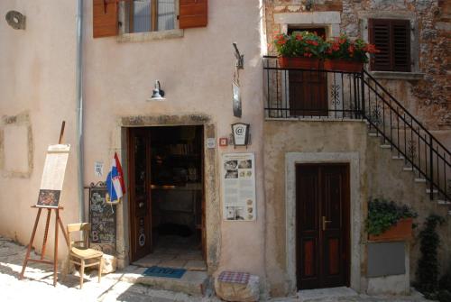 a building with a door and a balcony with a flower pot at Kamene Priče rooms, music and food in Bale