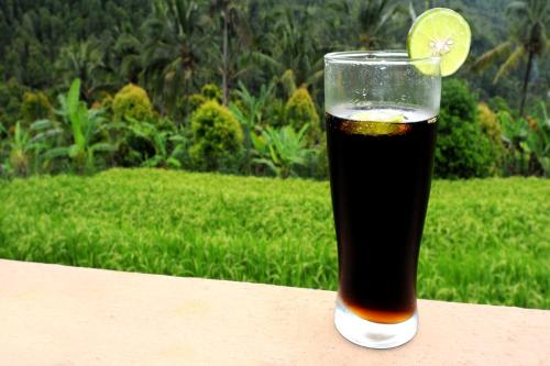 a glass of beer with a lime on a table at Gangga Homestay in Munduk