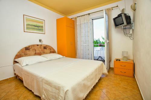 Schlafzimmer mit einem Bett, einem TV und einem Fenster in der Unterkunft Apartments Sijerkovic in Herceg-Novi