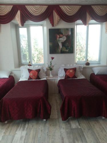 ヘルソンにあるGuest House Comfortの赤いシーツと窓が備わるベッド2台付きの客室です。