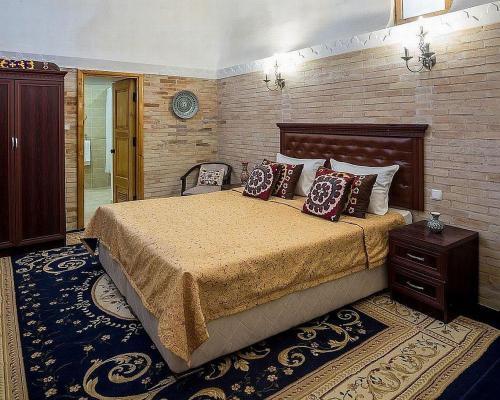a bedroom with a large bed and a brick wall at Orient Star Khiva Hotel- Madrasah Muhammad Aminkhan 1855 in Khiva