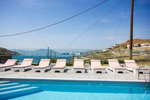 a group of lounge chairs next to a swimming pool at Anixi - Primavera Mykonos in Ornos